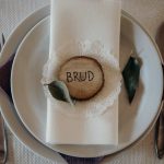 A refined table setting showcasing wedding decor with a wooden 'Brud' ornament and fine cutlery.