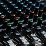 Detailed view of an audio mixing console with colorful lights in a professional studio setting.